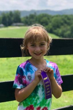 proud student holds her HorseSense camp ribbon